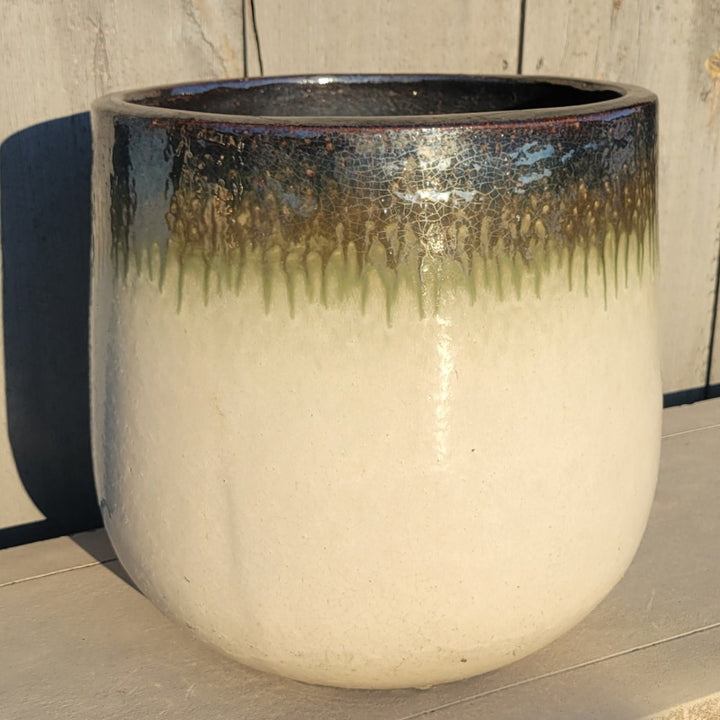 A tall oval planter with straight walls, finished in a cream-white to olive green to reflective mirror black ombre.