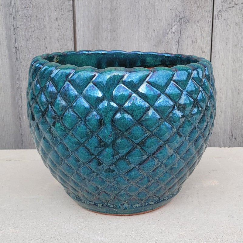 A rounded Teresa Planter with carved geometric square design and scalloped lip; finished in a dark blue-green glaze.