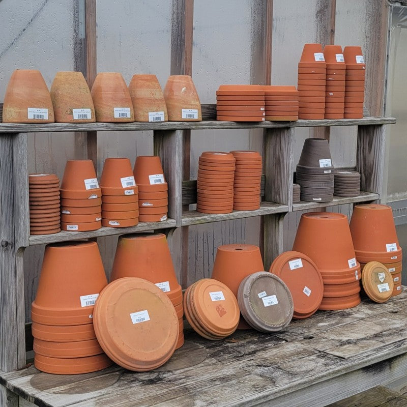 An assortment of red and dark gray terracotta planters and saucers.