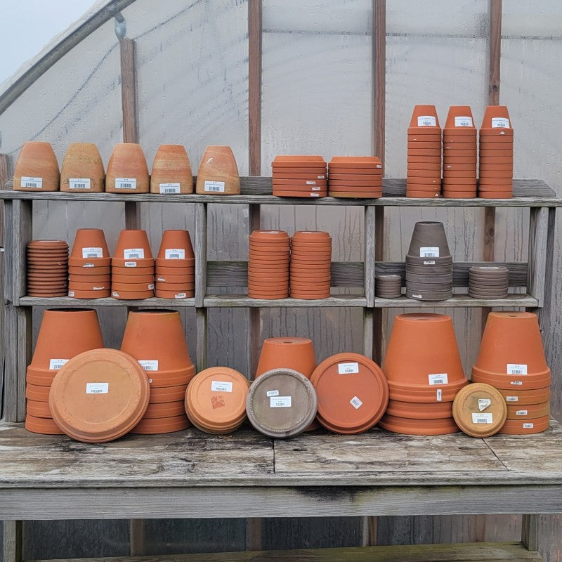 An assortment of red and dark gray terracotta planters and saucers.