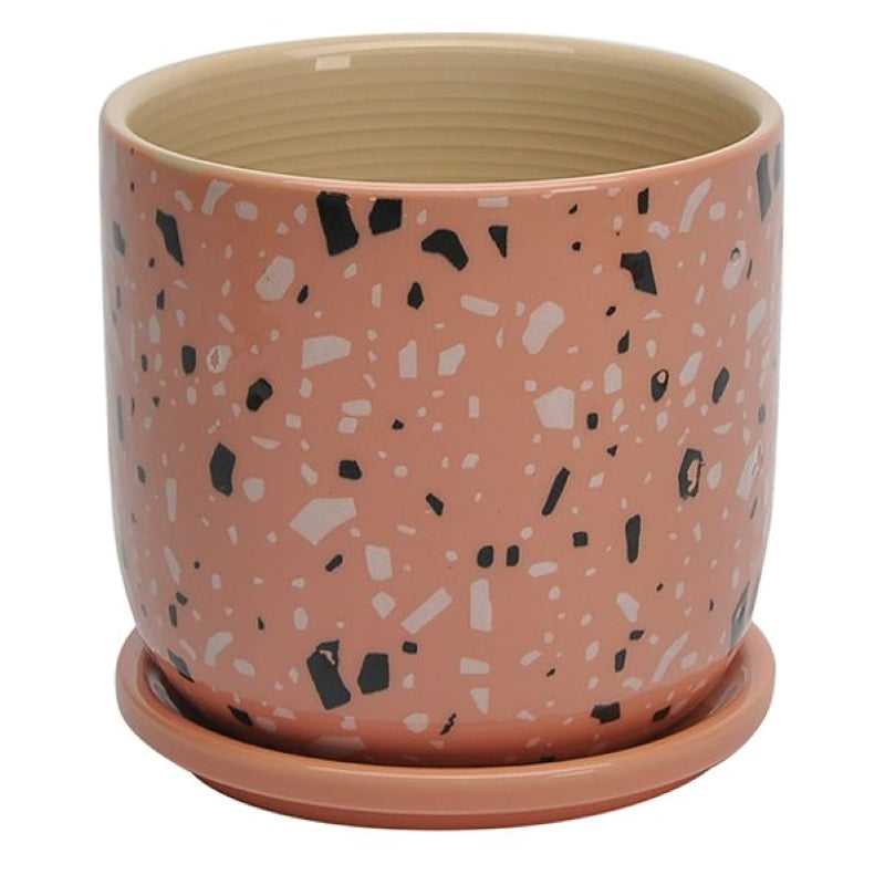 A stock photo of a round, straight-walled planter with built-in saucer; the planter's plain sides are decorated with a pink faux-terrazzo style glaze.