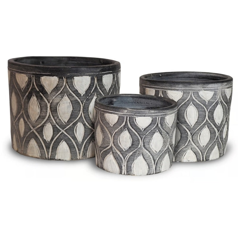 A stock photo of a trio of rounded planters with straight walls; planters are designed with a carved mid-mod diamond design and are finished with matte black and white paint.