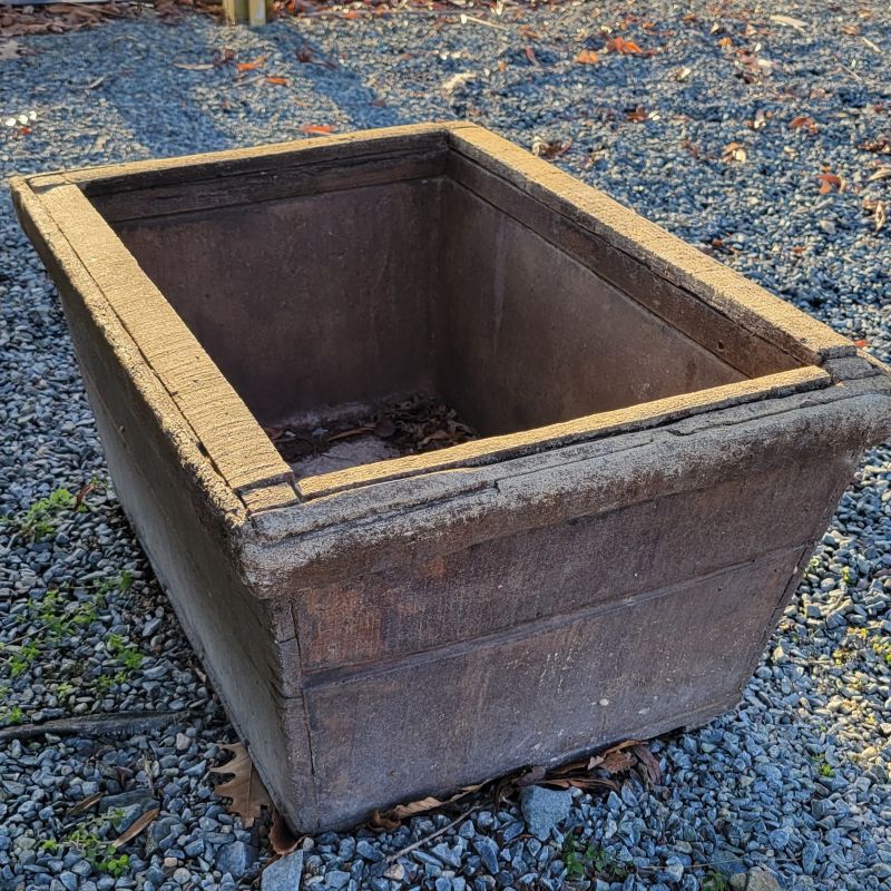 A low, rectangular, cast-stone planter with faux-wood exterior design, texture, and glaze color.