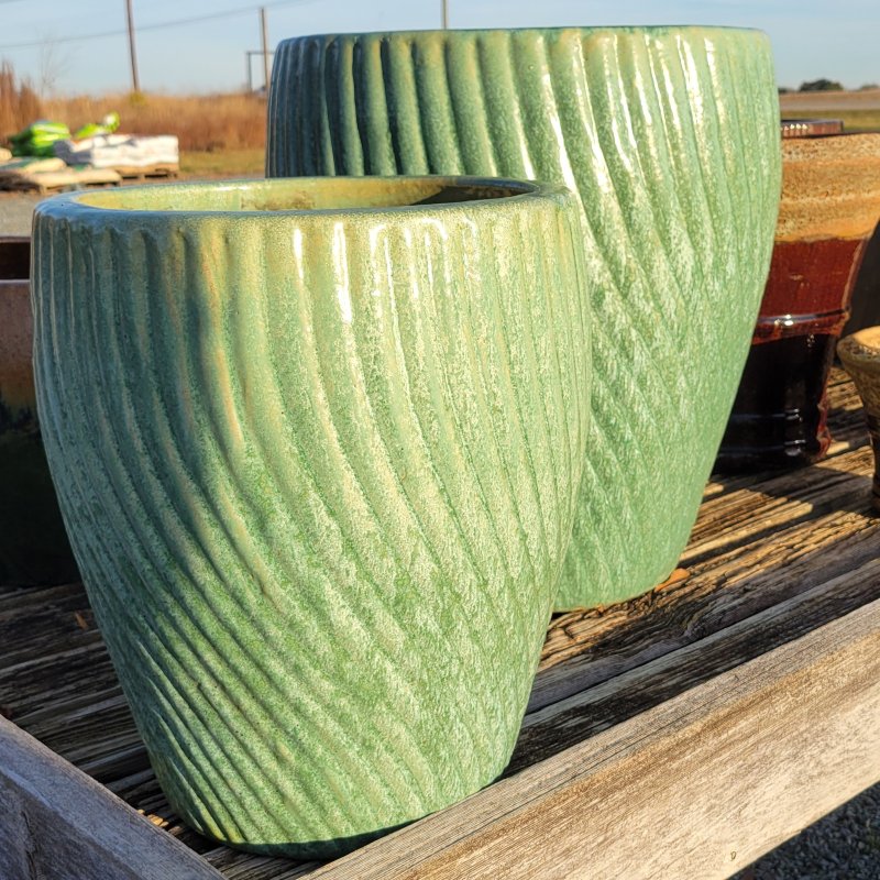 A pair of upright, rounded planter with a sculpted swirling vortex design; finished in a pearlescent seafoam green Celadon Pearl glaze.