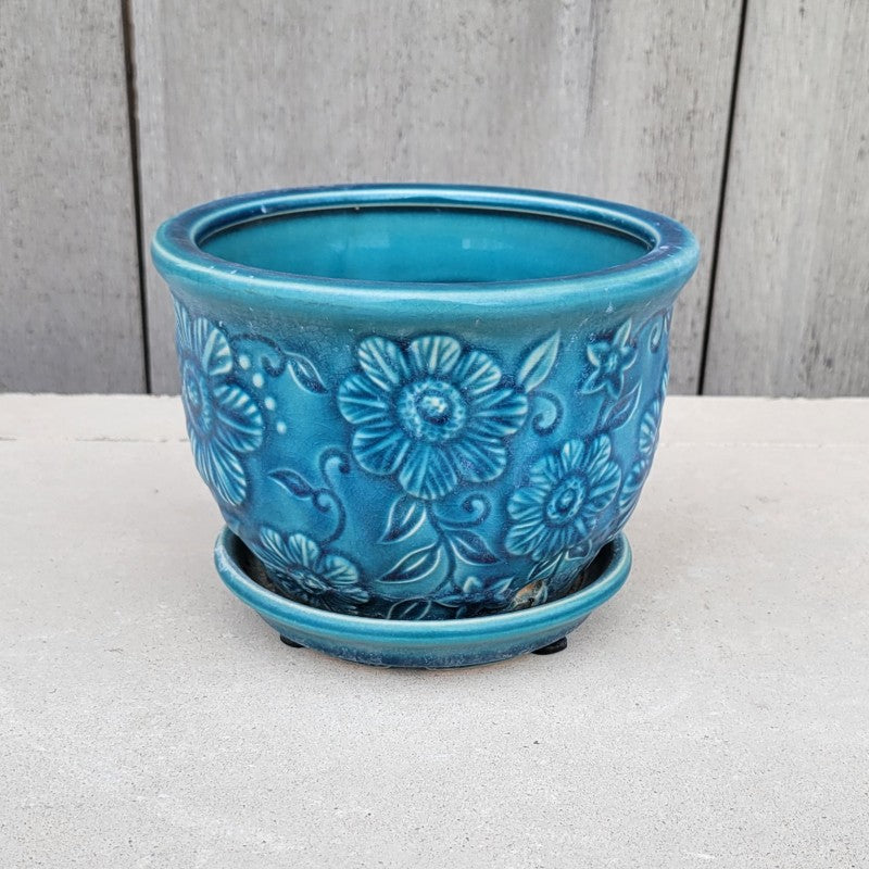 A small, rounded planter with built-in saucer and sculpted wildflower design. Finished with a distressed blue glaze.